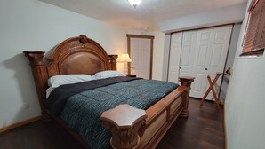 Een slaapkamer met een houten bed, een nachtkastje, een lamp en een kledingkast.