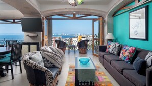 Un balcón amplio con vistas al horizonte de la ciudad, amoblado con un sofá, sillas y una mesa de comedor.