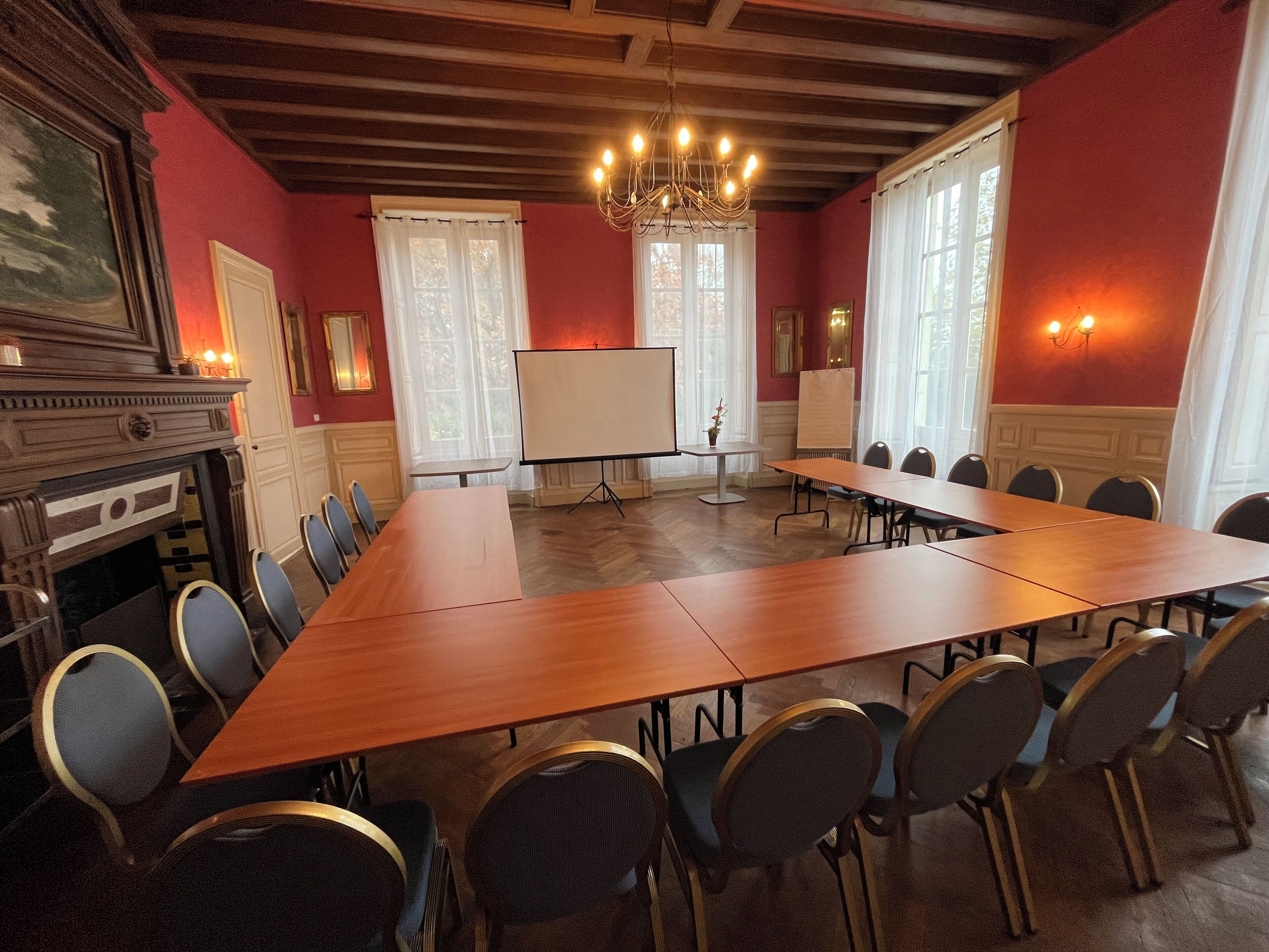 A conference room with a long table, chairs, a whiteboard, and a fireplace.