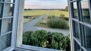 Une vue depuis une fenêtre, avec un ciel dégagé et un paysage rural.