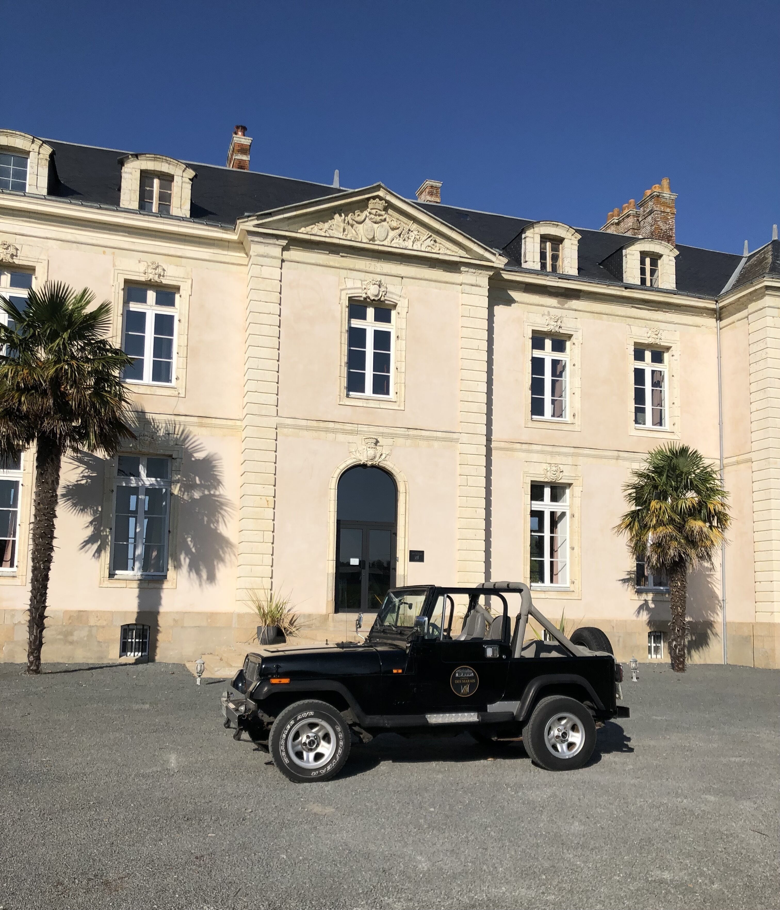 A black off-road vehicle parked in front of a large, classical building with multiple windows and a central entrance.