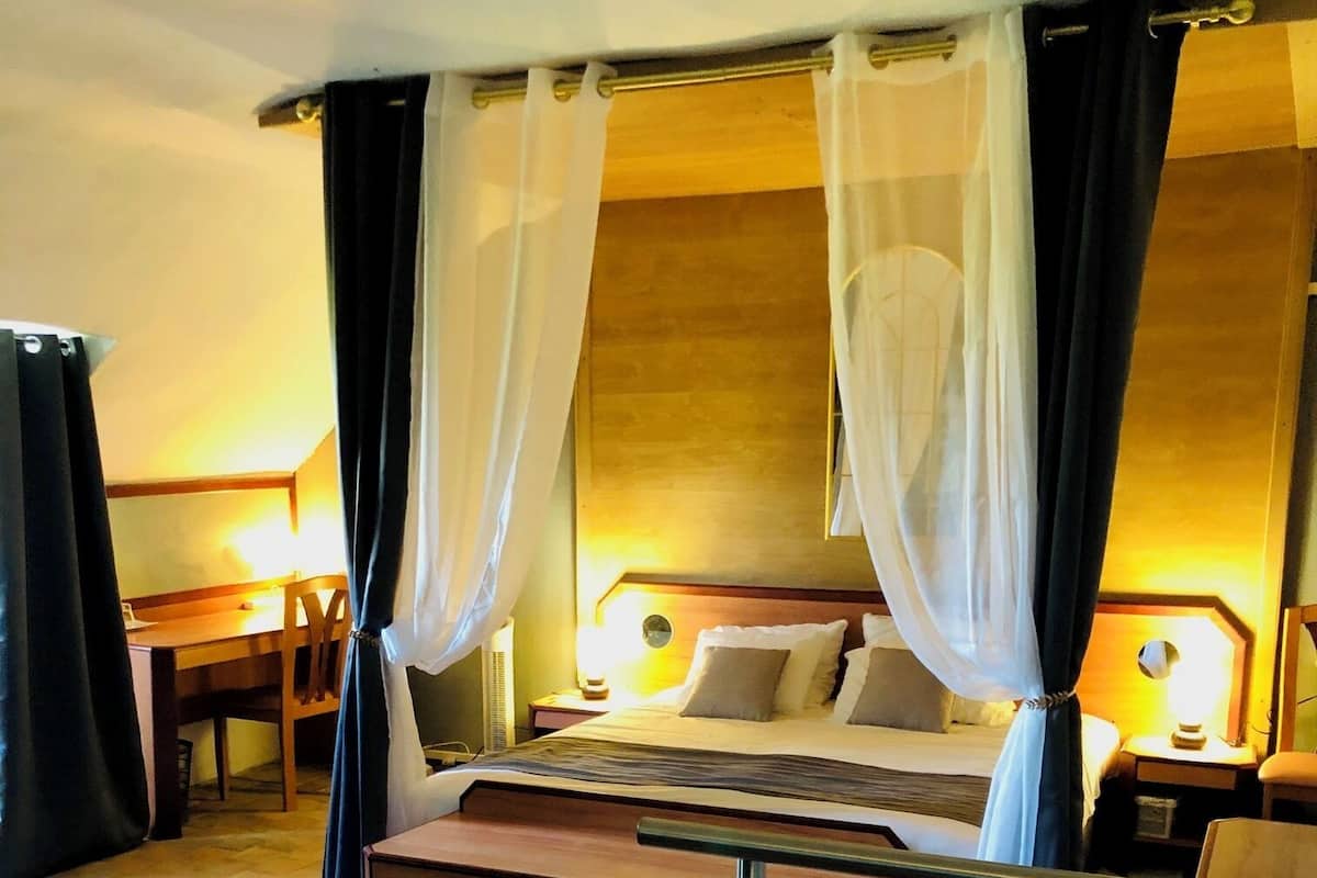 Une chambre d’hôtel avec un grand lit, une table de chevet, une chaise et un bureau avec une autre chaise.