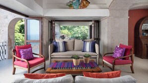 A balcony with a sofa, chairs, and a ceiling fan. - Rent the Entire Floor at Luxury Resort: 5th Floor Suites Spectacular Ocean Views (Puerto Vallarta)