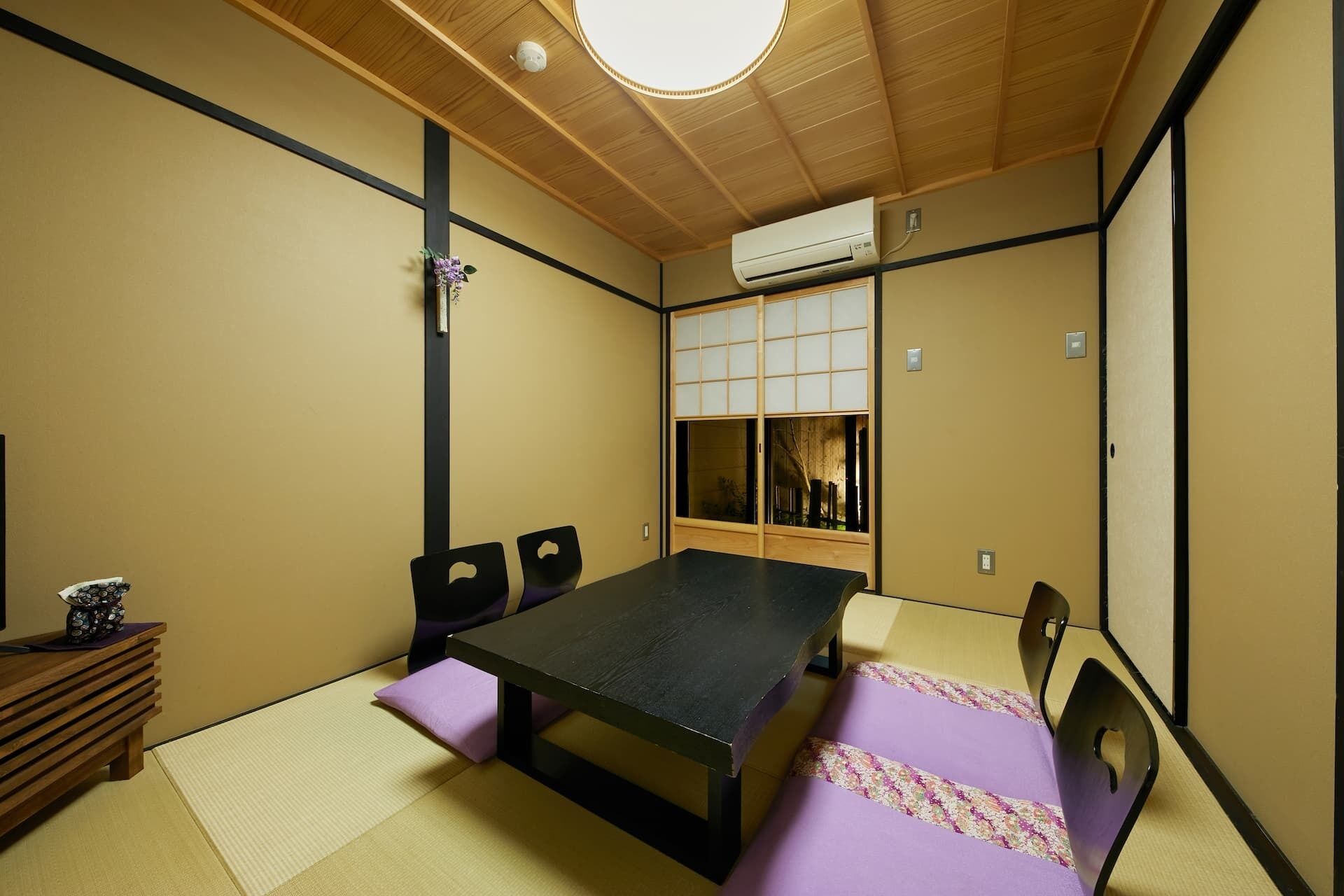 A traditional Japanese room with tatami flooring, a low table, and a futon bed.