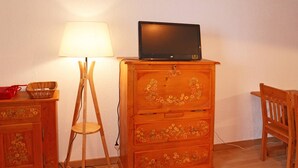 A wooden dresser with a television on top, a lamp, and a chair.
