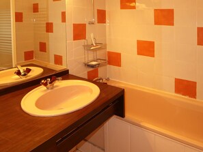 Une salle de bain avec un lavabo blanc, un miroir et une baignoire.