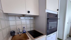 A compact kitchen with a sink, a stove, and a built-in oven. - Cozy Studio Cabin with Terrace & Parking, 4 Sleeps, Near Beach, Le Grau-du-Roi (Le Grau-du-Roi)
