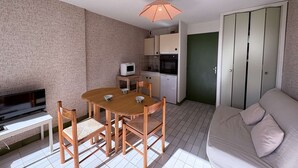 A compact living space with a dining area, kitchenette, and a sofa. - Cozy Studio Cabin with Terrace & Parking, 4 Sleeps, Near Beach, Le Grau-du-Roi (Le Grau-du-Roi)
