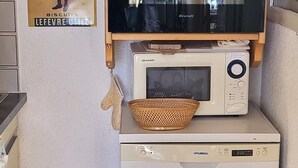 A compact kitchen with a microwave, a small oven, and a dishwasher stacked on top of each other.