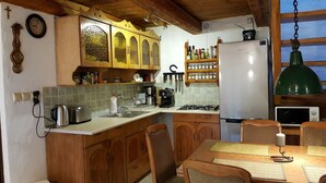 Eine Küche mit Holzschränken, einem Edelstahlkühlschrank, einer Kaffeemaschine und einem Esstisch mit Stühlen.