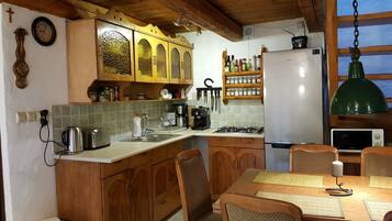 Eine Küche mit Holzschränken, einem Edelstahlkühlschrank, einer Kaffeemaschine und einem Esstisch mit Stühlen.