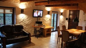Ein gemütliches Wohnzimmer mit einer Ledersofa, einem Holzes Esstisch und einem an der Wand befestigten Fernseher.
