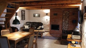 Ein gemütliches Wohnzimmer mit Kamin, Holzmöbeln und einer Treppe zu einer oberen Ebene.