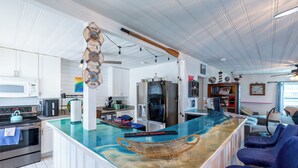 A modern kitchen with a central island, built-in appliances, and a seating area with blue chairs.
