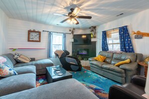 A living room with a ceiling fan, a fireplace, a sofa, a coffee table, and a television.