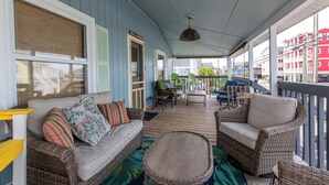 A covered porch with wicker furniture, a wooden table, and a view of the street.