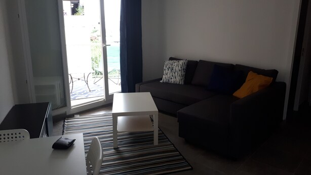 Un salon comprenant un canapé, une table basse, un téléviseur et une porte-fenêtre coulissante donnant sur un espace extérieur.