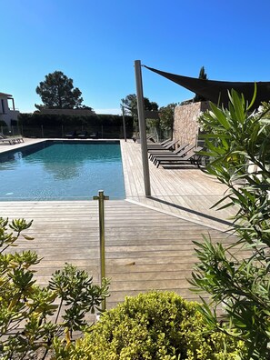A swimming pool with a wooden deck, lounge chairs, and a stone wall. - VILLA U SANDA 3 minutes from the beach (Lecci)