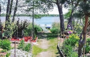Ein Gartenweg führt zu einem Steg an einem See, umgeben von Pflanzen und Bäumen.