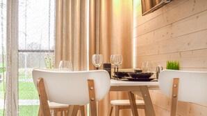 Een eethoek met een tafel voor twee personen, stoelen en uitzicht op groen.