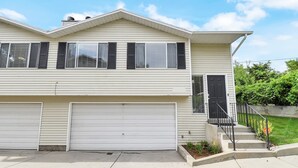 A two-story house with a garage, a front door with a small porch, and a well-maintained lawn.