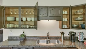 A kitchen with open cabinets displaying glassware, plates, and bowls.