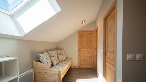 Un dormitorio tipo loft con techo inclinado, una cama de madera, tragaluces y una puerta grande de madera.