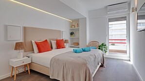 Una camera da letto moderna con un letto grande, comodini, un tavolino, una lampada, una pianta in vaso e una finestra con persiane.