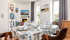 Zona pranzo con tovaglia a tema nautico, camino e televisore a parete.