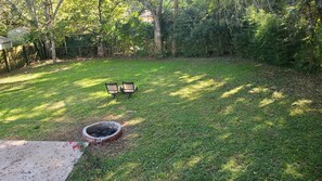 Relax in a serene space surrounded by lush greenery, with a fire pit and comfortable seating for two.