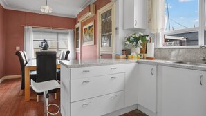 A kitchen with white cabinets, a granite countertop, a dining area with a table and chairs, and a window with a 'No Smoking' sign. - A cozy art deco farmhouse within walking distances to all amenities in town. (Te Awamutu)