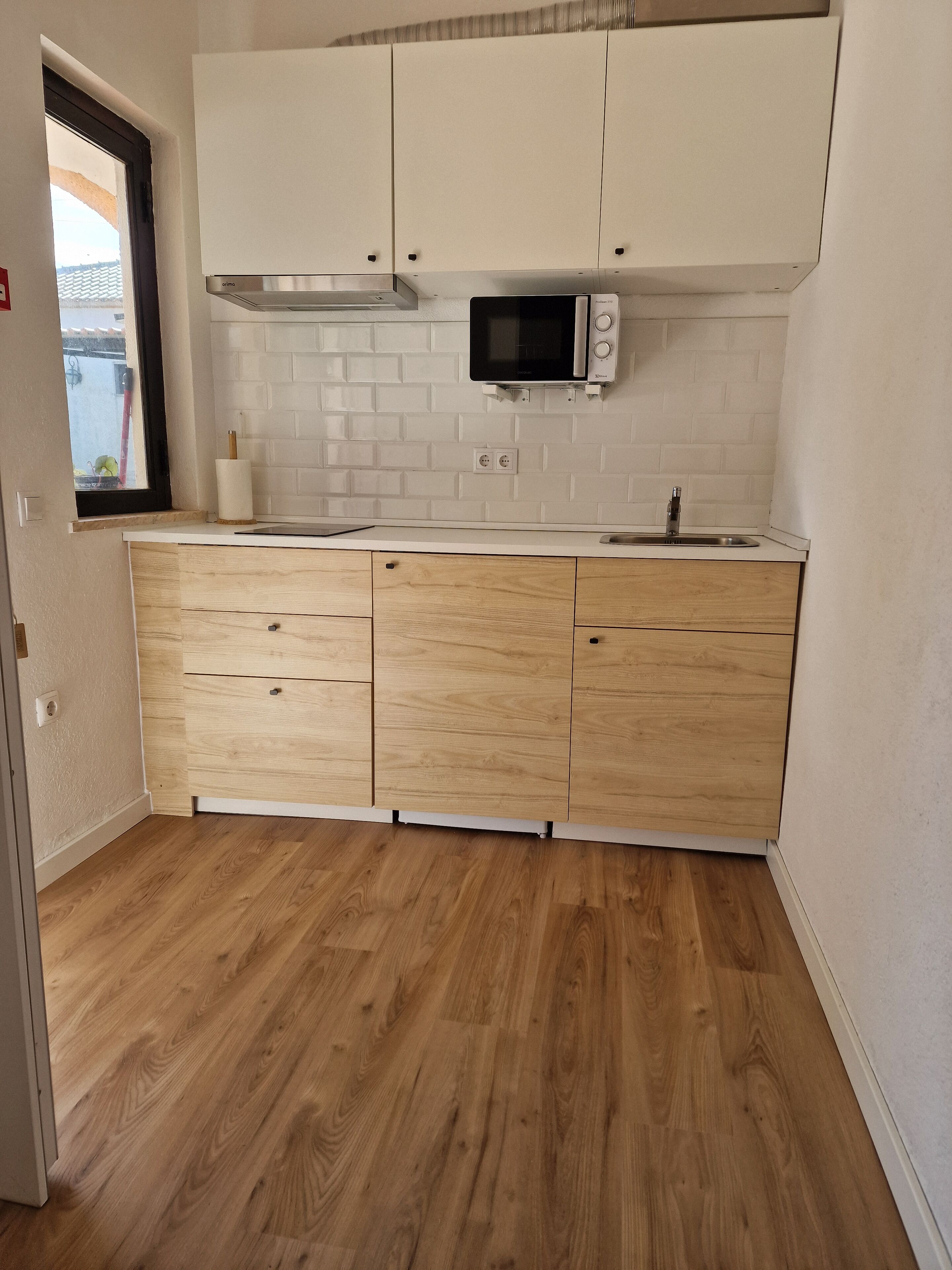 A kitchen with white cabinets, a microwave, and a wooden countertop.