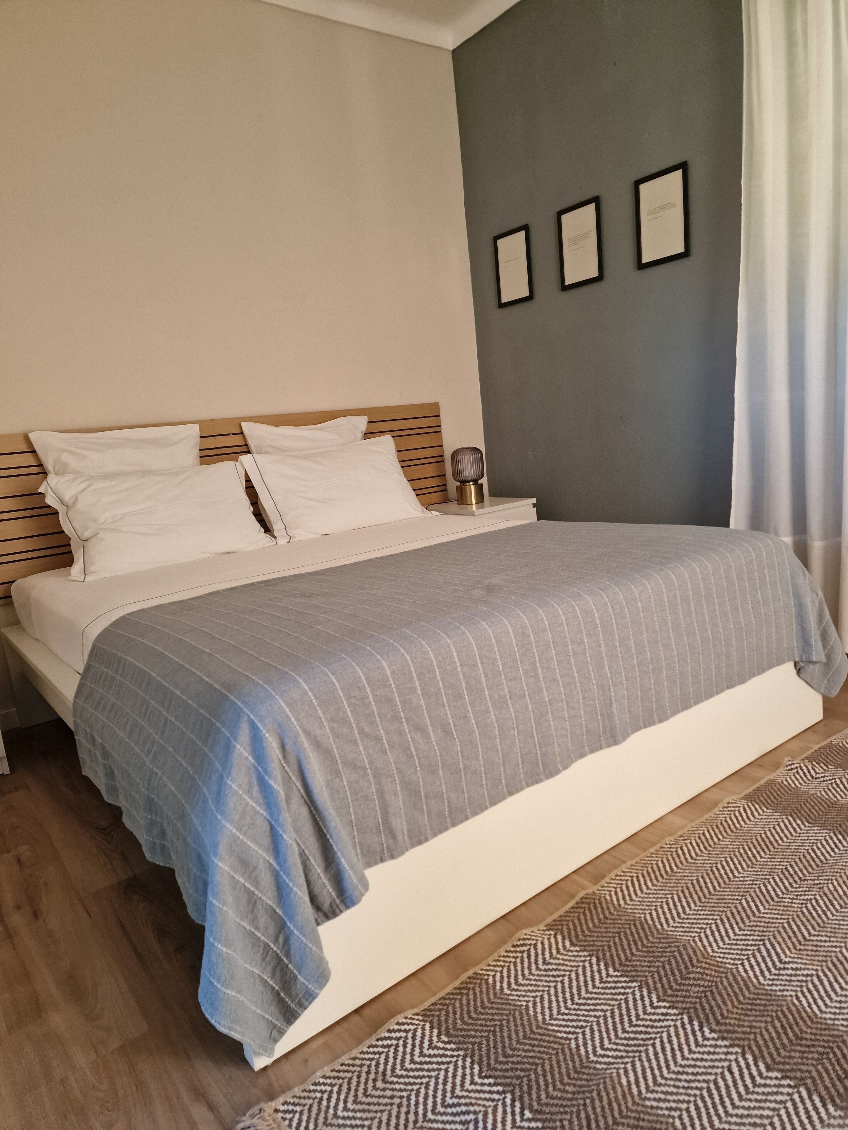 A neatly made bed with a striped blanket, a wooden headboard, and a bedside table with a lamp.
