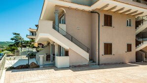A multi-story building with a central staircase, balconies, and a paved courtyard.