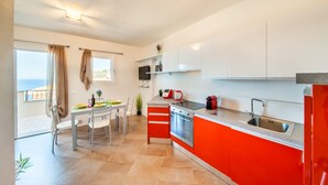 A modern kitchen with white and red cabinets, a stainless steel sink, and a dining area with a table and chairs.