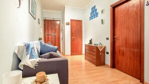 A living room with a sofa, a coffee table with a cake, and a dresser. There are wooden doors and a hallway leading to another room. - Pet friendly apartment in Follonica with WiFi (Follonica)
