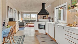 A modern kitchen with a black range hood, white cabinets, and a large window. - 3 bedroom stunning home in Juelsminde (Juelsminde)