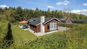 A modern house with a patio, a chimney, and a red umbrella. - 3 bedroom stunning home in Juelsminde (Juelsminde)