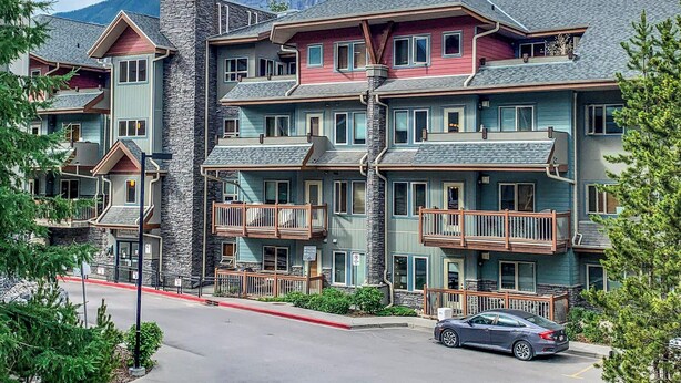 Un hôtel à plusieurs étages, doté de balcons et offrant une vue sur les montagnes.