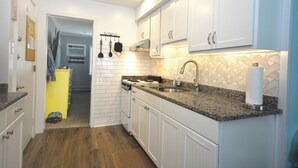 Una cocina con gabinetes blancos, encimeras de granito y un salpicadero de azulejos.