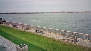 Un paseo marítimo con muelle de madera, zonas de estar y césped.