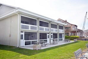 Un bâtiment à deux étages doté d’un patio couvert, de tables de pique-nique et d’un petit jardin.