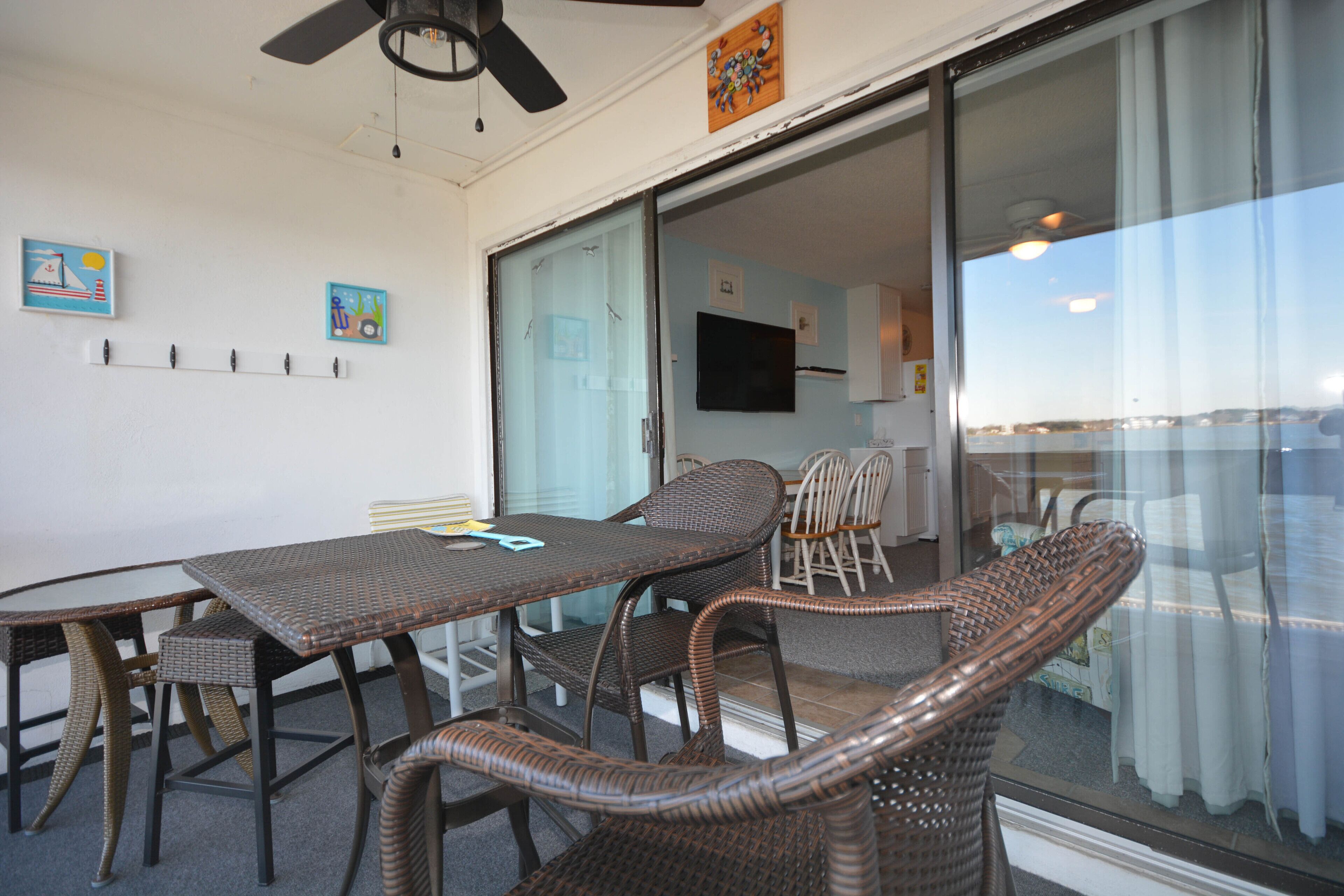 A dining area with wicker furniture, a ceiling fan, and a view through a glass door.