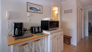 A kitchen with a coffee maker, toaster, microwave, and a wooden bar counter.