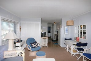Relax in a cozy living area with a nautical theme, featuring a comfortable seating arrangement and a dining table.