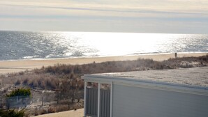 A beach view with a sandy shore, a wooden fence, and a white building.