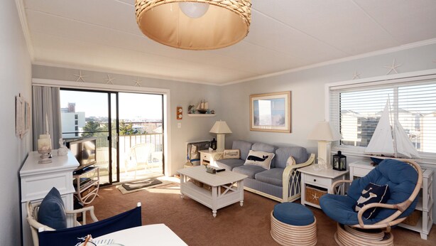 A spacious living room with a large window, a ceiling fan, a sofa, a coffee table, and a chair.