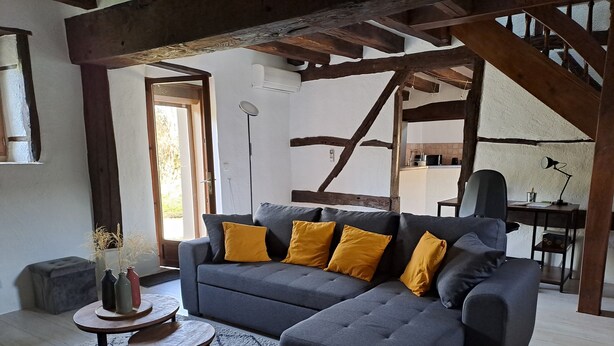 A living room with a grey sectional sofa, yellow cushions, a small round table, and a woven basket. - La Chaumière de Chabine (OIZON)