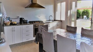 A compact kitchen with white cabinets, a stove, and a large window. - Casa con Jardin en el Salnes (Meaño)