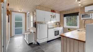 A compact kitchen with white cabinetry, a built-in oven, a microwave, and a window with a view of trees. - 3 bedroom amazing home in Oksbøl (Oksbøl)